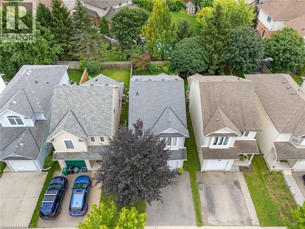 Grey shingle roof, attached garage, paved driveway, mature trees, and a private backyard - 711 Angler Way, Waterloo, ON - Outdoor