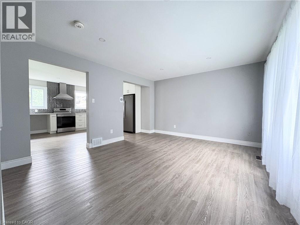 Spacious room featuring wood-finish flooring, recessed lighting, and light gray wall paint - 216 Brunswick Crescent, London, ON