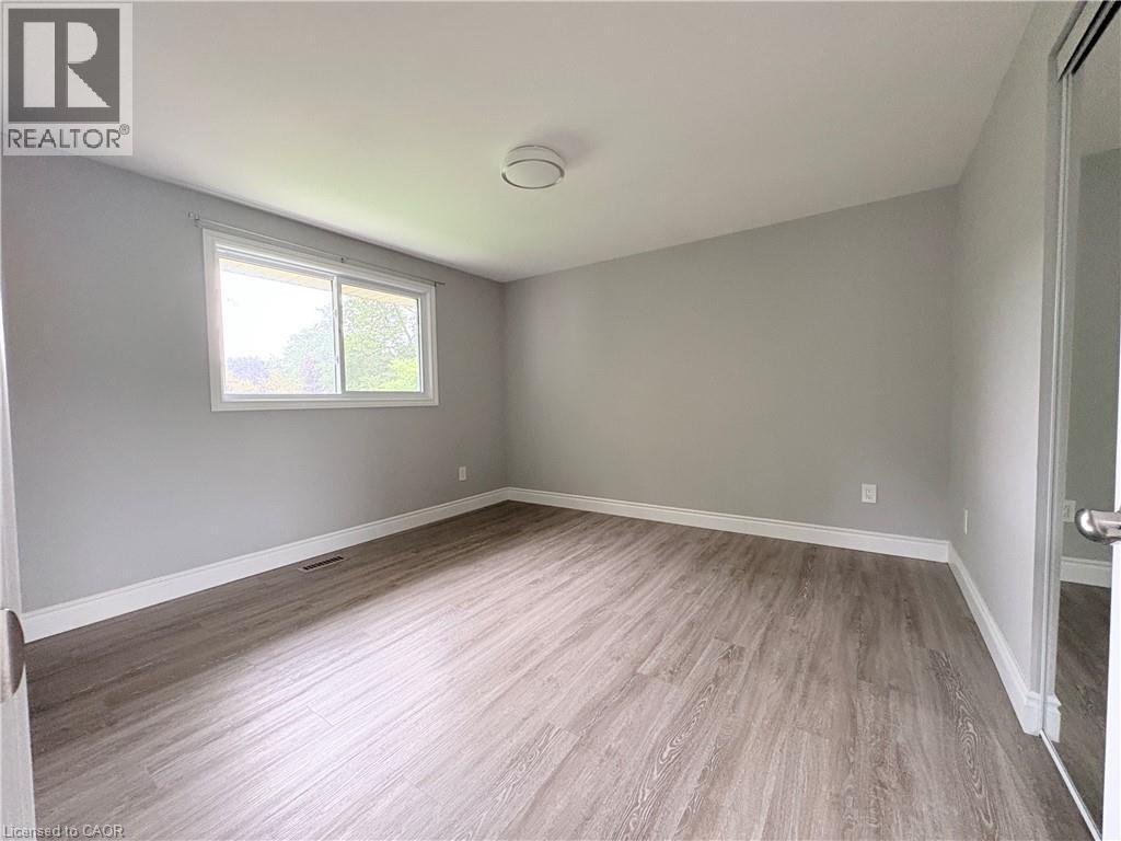 Light gray wall paint, wood-finish flooring, white window trim, white baseboards, and a semi-flush mount ceiling fixture - 216 Brunswick Crescent, London, ON