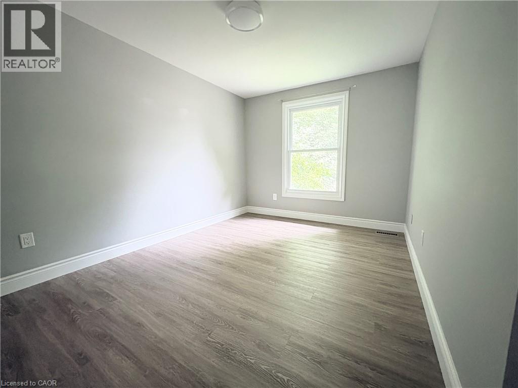 Wood-finish flooring with white trim, a double-hung window, light gray walls, and a flush-mount ceiling light - 216 Brunswick Crescent, London, ON