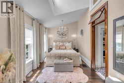 Primary bedroom with soaring ceiling and architectural salvage door, complete with functional transom. - 