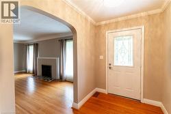 Entryway featuring a white door with decorative glass inserts, wood-finish flooring, and crown molding - 