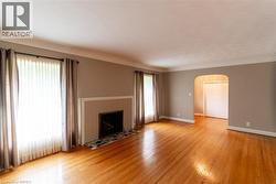 Spacious interior featuring wood-finish flooring, a fireplace with a light-toned tile surround, and an arched doorway - 