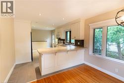 Kitchen featuring white cabinetry, a peninsula with seating, tile flooring, and a subway tile backsplash - 