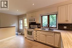 Kitchen featuring light-toned cabinetry, light wood-finish countertops, and a dark subway tile backsplash - 