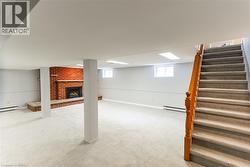 Spacious lower level featuring light-toned carpeting and a prominent brick fireplace with a hearth - 