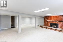 Spacious lower level featuring light-colored carpeting and a brick fireplace with a stone hearth - 