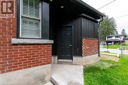 Exterior featuring red brick and dark vertical siding, concrete foundation, and a solid black entry door - 