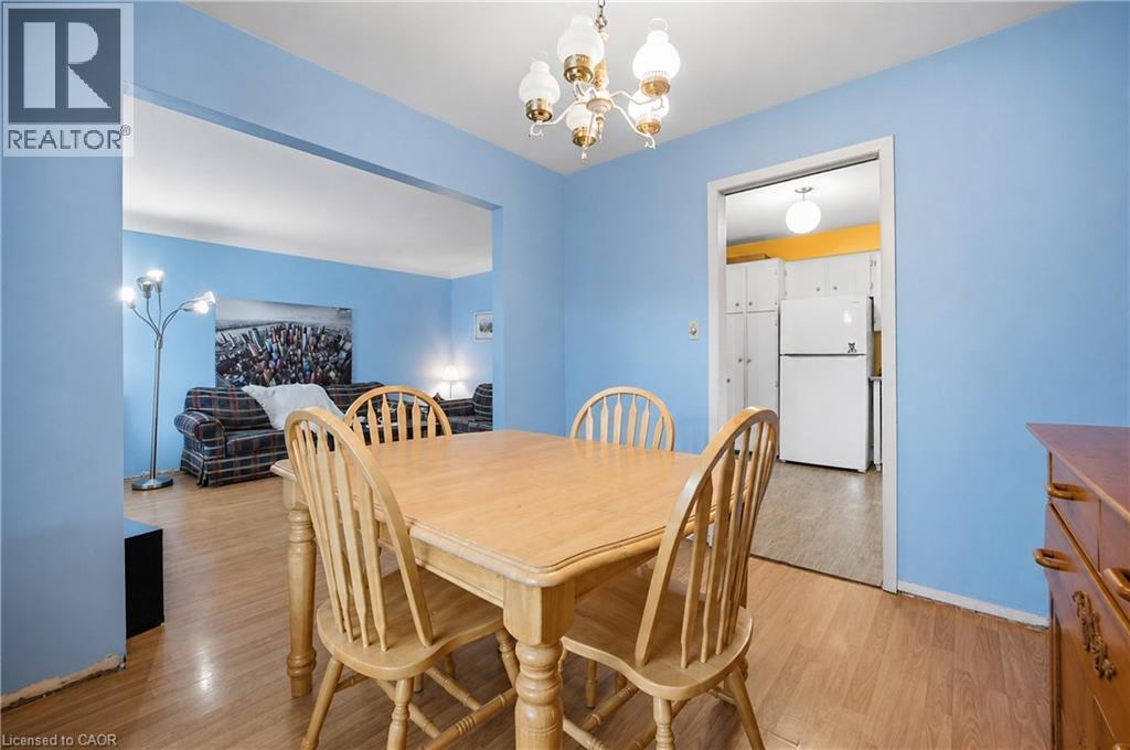 Dining area featuring wood-finish flooring, a decorative ceiling light fixture, and an open doorway to the kitchen - 11 Kimbermount Drive, St. Catharines, ON - Indoor Photo Showing Dining Room