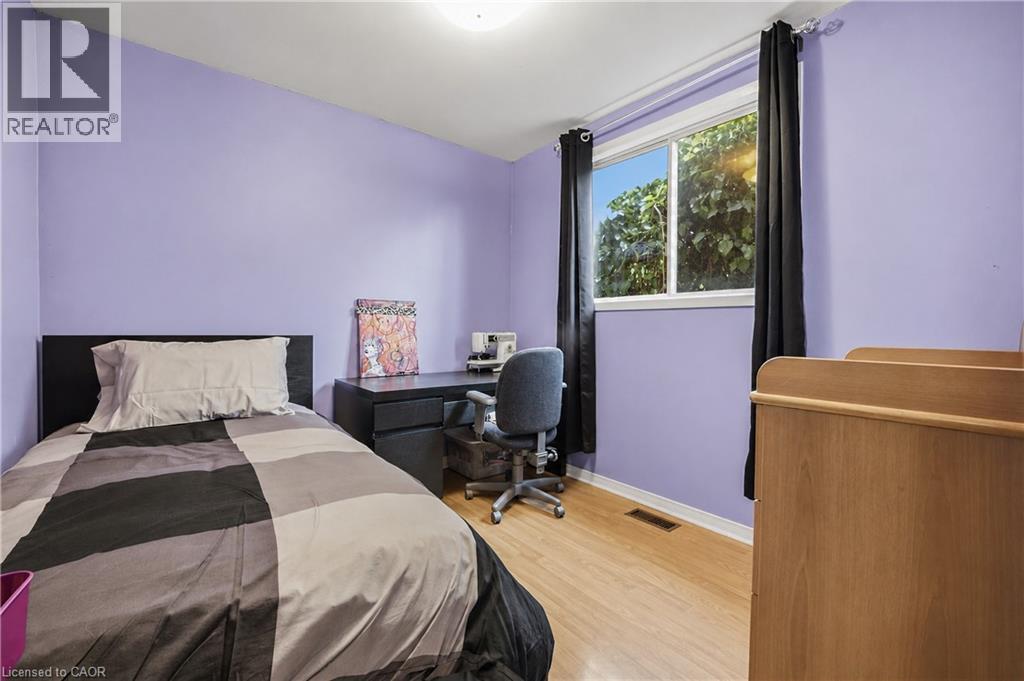Room featuring light purple walls, wood-finish flooring, and a single window with dark window treatments - 11 Kimbermount Drive, St. Catharines, ON - Indoor Photo Showing Bedroom