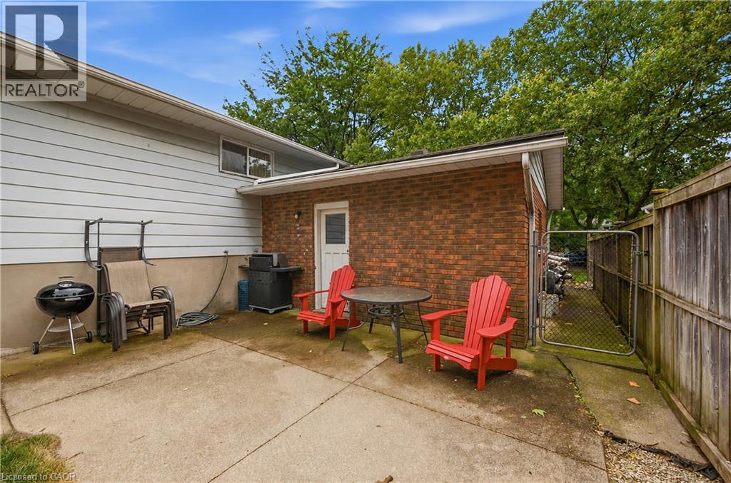Concrete patio area featuring a brick exterior extension and chain-link gate - 11 Kimbermount Drive, St. Catharines, ON - Outdoor With Deck Patio Veranda With Exterior
