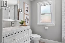 White vanity with integrated sink, chrome faucet, wall-mounted mirror, white subway tile shower surround, and window with white trim -