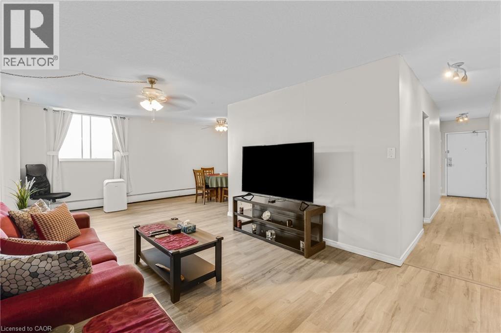 Wood-finish flooring throughout, bright white walls, and track lighting in the hallway - 975 Warwick Court Unit# 708, Burlington, ON - Indoor Photo Showing Living Room