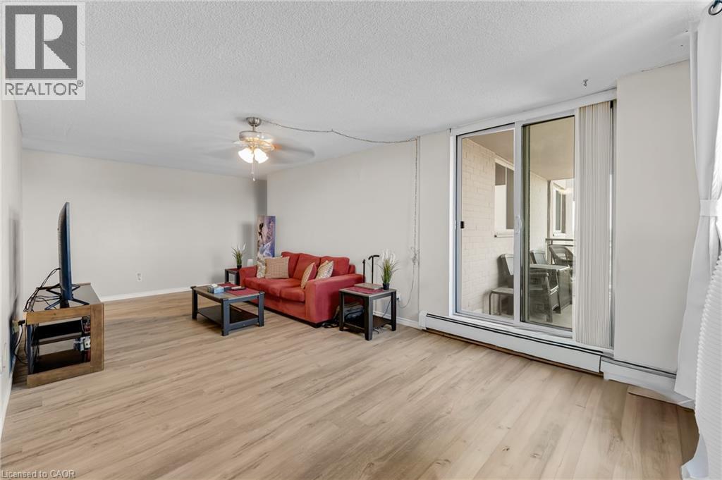 Spacious living area featuring wood-finish flooring, a ceiling fan, and sliding glass doors leading to an outdoor space - 975 Warwick Court Unit# 708, Burlington, ON - Indoor