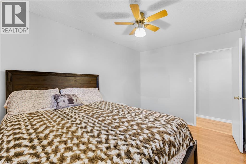Wood-finish flooring, ceiling fan with integrated lighting, and a solid wood headboard - 975 Warwick Court Unit# 708, Burlington, ON - Indoor Photo Showing Bedroom