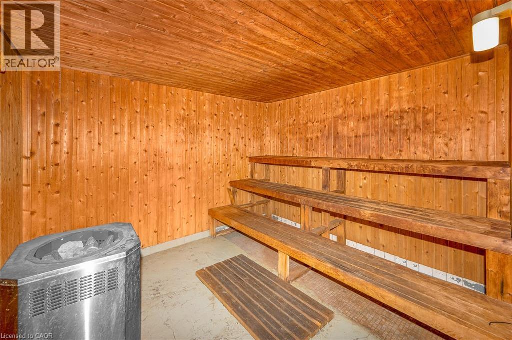 Sauna featuring wood paneling, multi-tiered wood bench seating, and a metallic sauna heater - 975 Warwick Court Unit# 708, Burlington, ON - Indoor Photo Showing Other Room