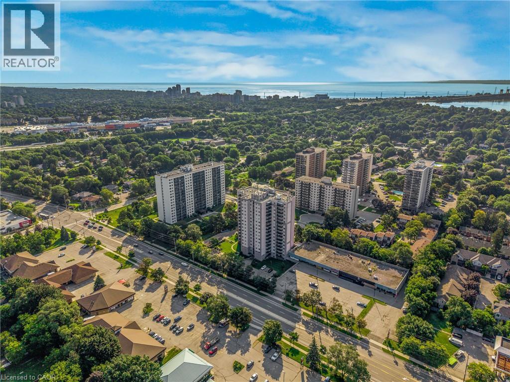 Expansive urban landscape featuring multiple high-rise buildings, mature tree canopy, and distant water views - 975 Warwick Court Unit# 708, Burlington, ON - Outdoor With View