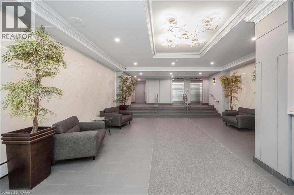 Recessed lighting, crown molding, marble-patterned wall panels, stainless steel elevators, and gray tile flooring - 975 Warwick Court Unit# 708, Burlington, ON - Indoor Photo Showing Other Room