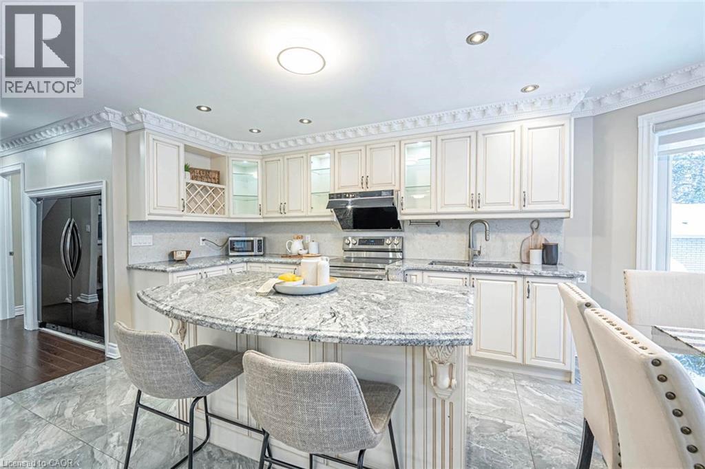Kitchen featuring an oversized island with a stone countertop, white cabinetry with decorative molding, stainless steel appliances, and large format floor tiles - 247 Sand Road, Holland Landing, ON - Indoor Photo Showing Kitchen With Upgraded Kitchen