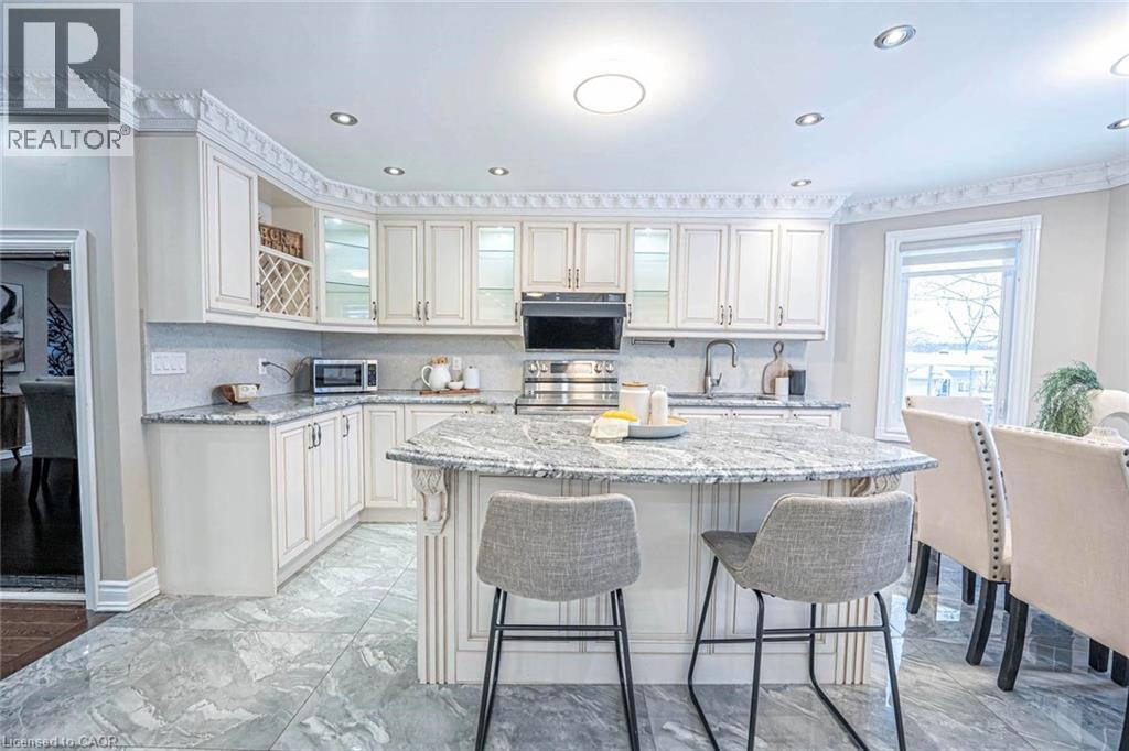 Kitchen featuring an expansive island with a stone countertop, extensive white cabinetry, recessed lighting, and tile flooring - 247 Sand Road, Holland Landing, ON - Indoor
