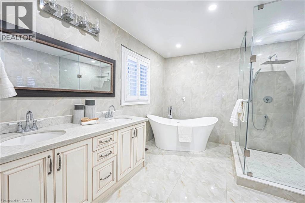 Bathroom featuring a freestanding soaking tub, frameless glass shower with rain showerhead, dual vanity with undermount sinks, and a large framed mirror - 247 Sand Road, Holland Landing, ON - Indoor Photo Showing Bathroom