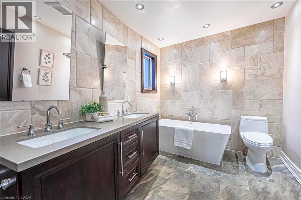 Contemporary bathroom featuring a freestanding tub and a dual-sink vanity with dark wood cabinetry and integrated sinks - 247 Sand Road, Holland Landing, ON - Indoor Photo Showing Bathroom