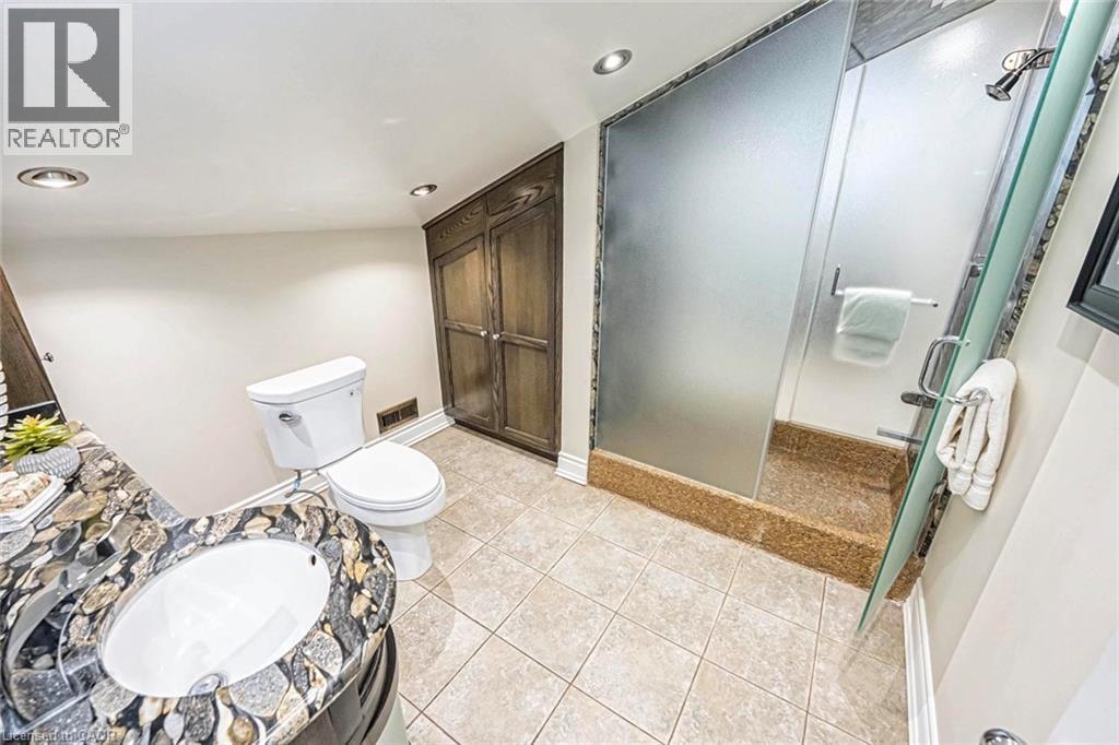 Bathroom featuring a vanity with an integrated sink and mosaic stone countertop, a white toilet, and a shower enclosure with frosted glass panels and a stone base - 247 Sand Road, Holland Landing, ON - Indoor Photo Showing Bathroom