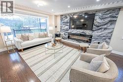 Living area featuring expansive window, hardwood flooring, detailed crown molding, a contemporary fireplace with a linear insert, and a striking stone-paneled accent wall -