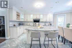 Kitchen featuring an expansive island with a stone countertop, extensive white cabinetry, recessed lighting, and tile flooring -