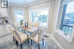 Bay window dining area with natural light, featuring tiled flooring, crown molding, and built-in cabinetry with stone countertops -