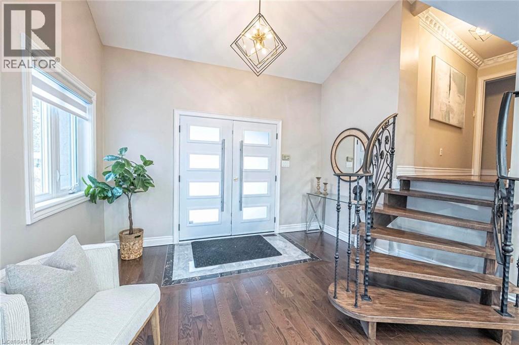Entryway featuring double doors with frosted glass panels, dark wood-finish flooring, a grand staircase with an ornate wrought-iron railing, vaulted ceilings, and a contemporary light fixture - 247 Sand Road, Holland Landing, ON - Indoor Photo Showing Other Room