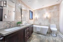 Contemporary bathroom featuring a freestanding tub and a dual-sink vanity with dark wood cabinetry and integrated sinks -