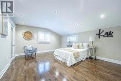 Spacious room featuring wood-finish flooring, recessed lighting, and a sloped ceiling -
