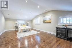 Spacious room featuring rich wood-finish flooring, recessed lighting, and multiple windows with plantation shutters -