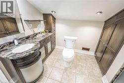 Bathroom featuring a vanity with a dark wood-finish base, integrated white sink, and a multi-toned stone countertop -