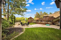 Spacious backyard featuring a multi-level wood deck, a prominent gazebo, and a stone-paved patio with a built-in stone fire pit -