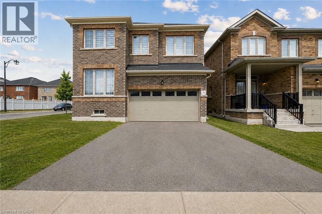Brick exterior with stone accents, attached garage, paved driveway, and established lawn - 525 Red Elm Road, Shelburne, ON - Outdoor With Facade