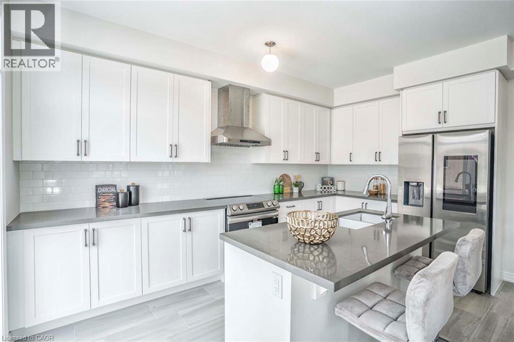 Kitchen featuring white shaker-style cabinetry, grey countertops, subway tile backsplash, and stainless steel appliances - 525 Red Elm Road, Shelburne, ON - Indoor Photo Showing Kitchen With Upgraded Kitchen