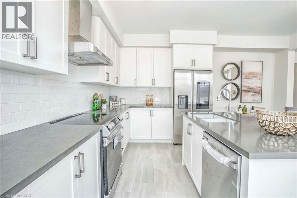 White shaker cabinetry, stainless steel appliances, grey countertop surfaces, white subway tile backsplash, and light-toned tile flooring - 525 Red Elm Road, Shelburne, ON - Indoor Photo Showing Kitchen With Upgraded Kitchen