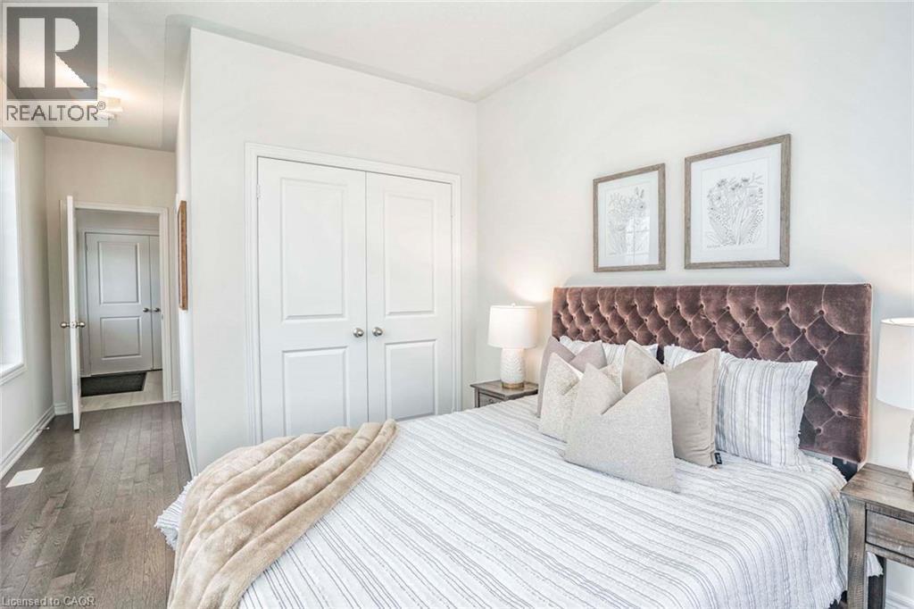 Wood-finish flooring throughout, white walls, and a double-door closet with paneling - 525 Red Elm Road, Shelburne, ON - Indoor Photo Showing Bedroom