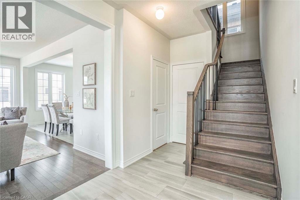 Wood-finish flooring, staircase with wood handrail and metal spindles, multiple pane windows, and a doorway with trim - 525 Red Elm Road, Shelburne, ON - Indoor Photo Showing Other Room