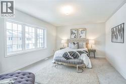 Bright room featuring a large window, neutral carpeting, and a ceiling-mounted light fixture -