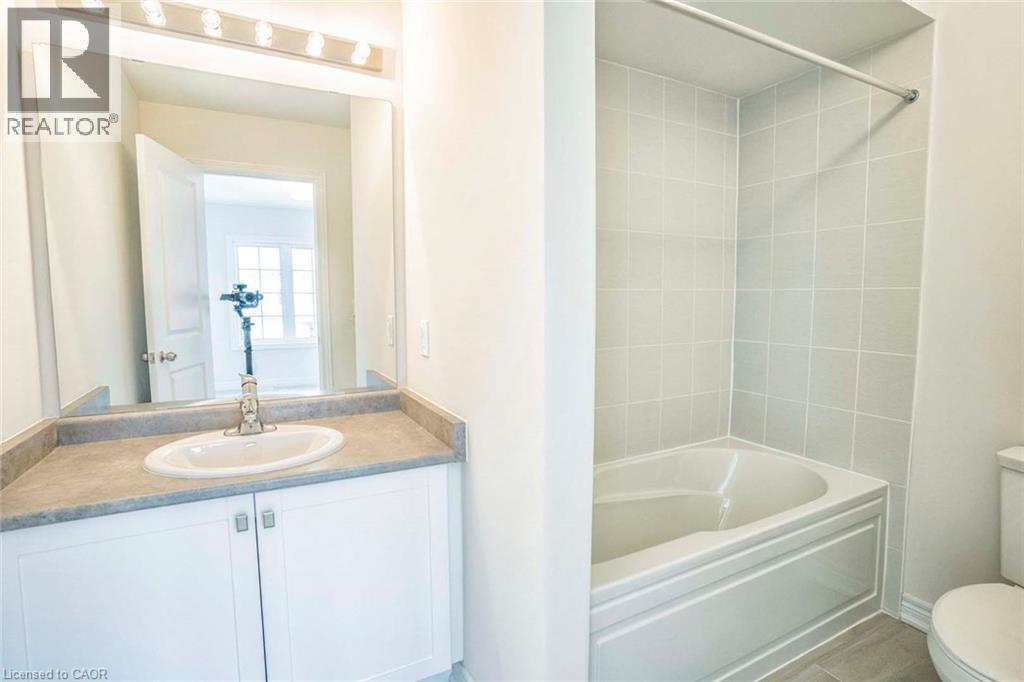 Vanity with a white oval sink, stone-finish countertop, and white cabinetry - 525 Red Elm Road, Shelburne, ON - Indoor Photo Showing Bathroom