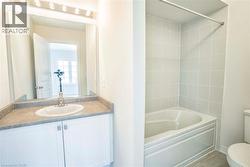 Vanity with a white oval sink, stone-finish countertop, and white cabinetry -