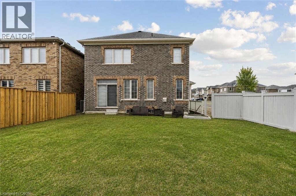 Expansive backyard with a manicured lawn, featuring a sliding glass door and a combination of wood and vinyl fencing - 525 Red Elm Road, Shelburne, ON - Outdoor