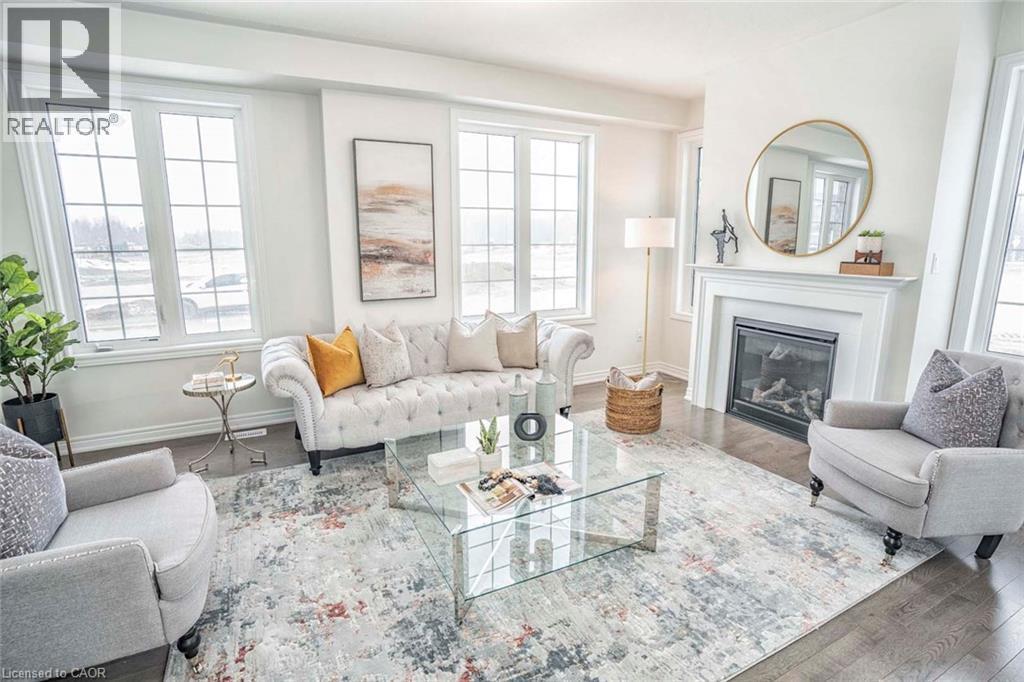 Hardwood flooring, multiple grid-pane windows, a built-in fireplace, and a white mantel - 525 Red Elm Road, Shelburne, ON - Indoor Photo Showing Living Room With Fireplace
