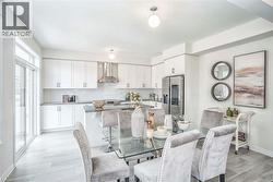 Modern kitchen featuring white cabinetry, stainless steel appliances, a center island with bar seating, and light-toned flooring -