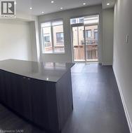 Spacious interior featuring a large kitchen island with a dark countertop, recessed lighting, wood-finish flooring, and a glass sliding door leading to a balcony - 