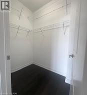 Walk-in closet with dark wood-finish flooring, white walls, and white wire shelving - 
