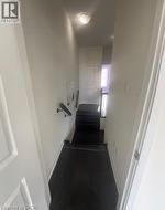Dark wood-finish stairs with white risers and a contrasting black handrail - 
